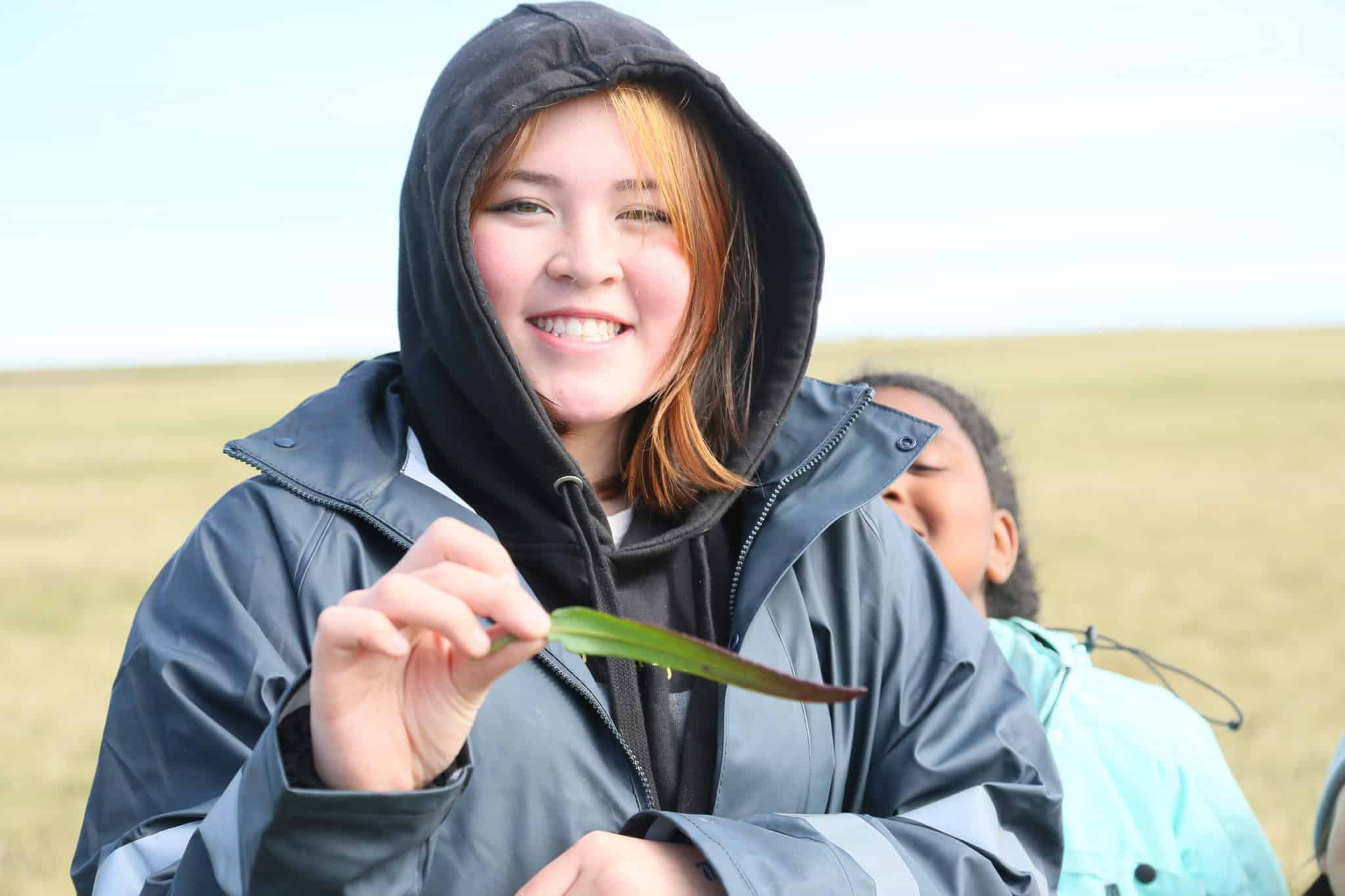 woman holds a plant and smiles