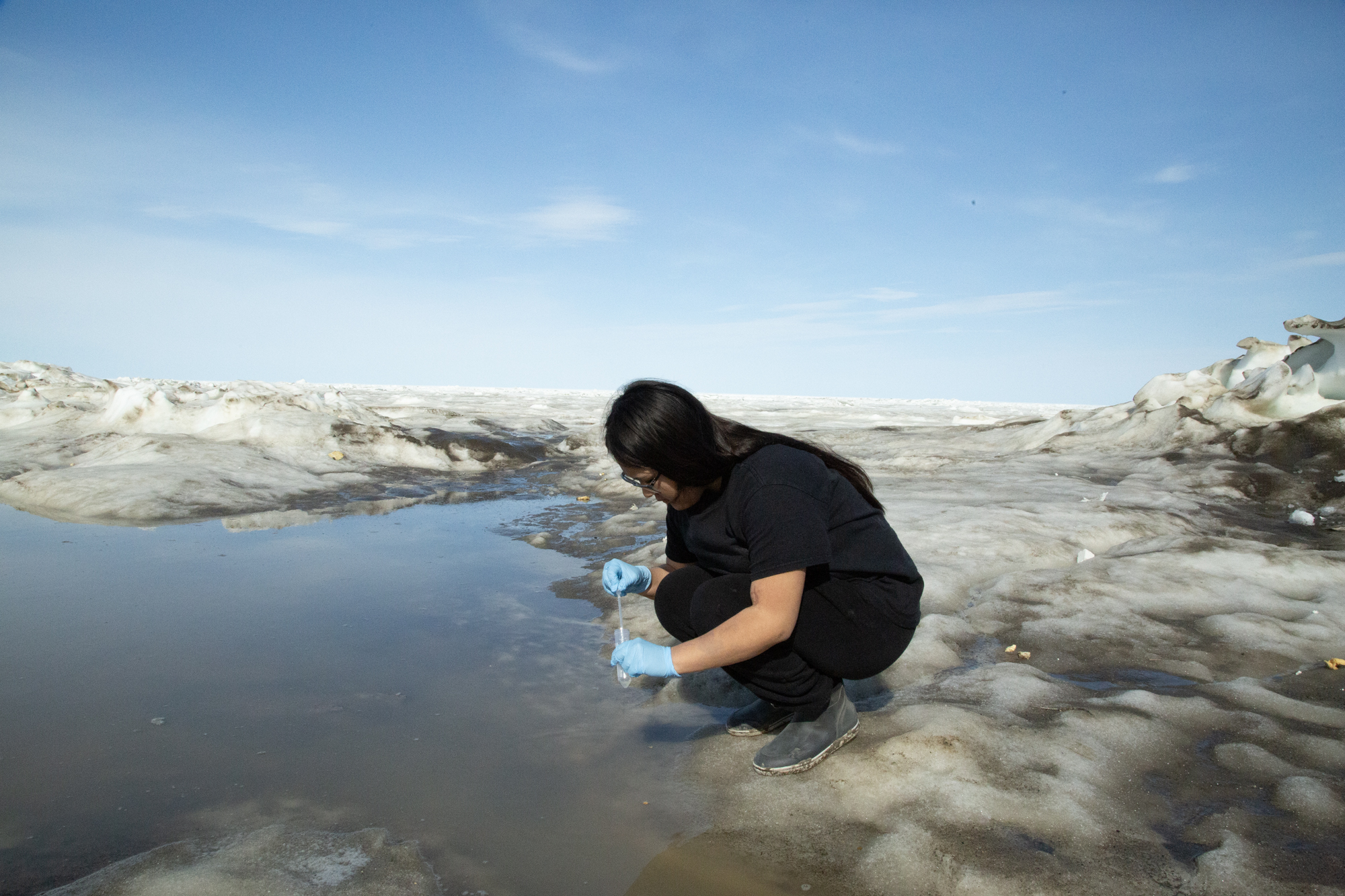 Summer camp student samples water from a melt pond